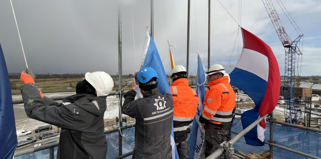 Bouwvakkers die vlaggen heisen bovenop het bouwproject