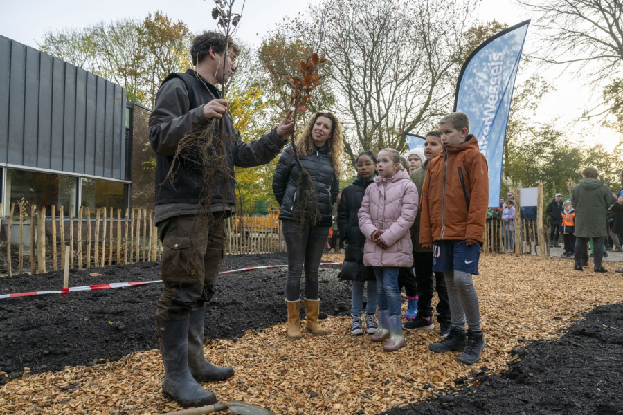 een volwassenen die praat tegen een groep kinderen met hun ouder/begeleider